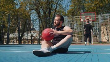 Portrait of tired smiling athletic lebanese man in sportswear relaxing after playing basketball game video