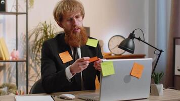 Tired sad exhausted businessman working on laptop at office with many sticker tasks, panic attack video