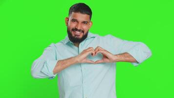 Smiling handsome man makes heart gesture demonstrates love sign expresses good feelings and sympathy video