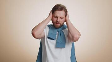 Annoyed irritated handsome man covering ears gesturing No avoiding advice ignoring noise loud voices video
