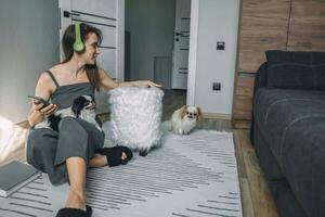 woman in casual wear with headphones interacting with her dogs in a modern living space, capturing a moment of joyful pet companionship photo