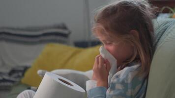 Sick girl blowing her nose with tissue sitting on couch at home video