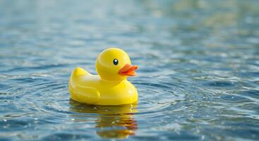 Yellow Rubber Duck Floating on Clear Water, creating ripple effect photo