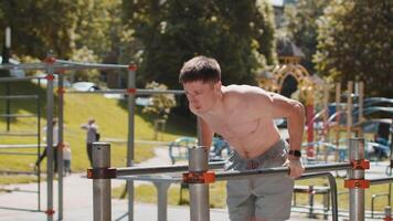 Athletic caucasian muscular man practicing dips on parallel bars training triceps on playground video