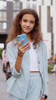 Preteen girl use smartphone typing text messages browsing internet finishing work looking at camera video