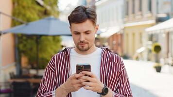 Bearded man use smartphone typing text messages browsing internet finishing work looking at camera video