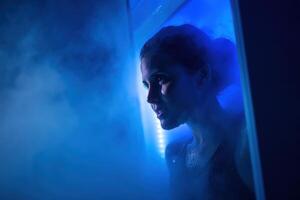 A person stands in a mist-filled chamber with blue lighting, showing a contemplative expression. The scene conveys a futuristic and atmospheric mood with contrasting shadows photo