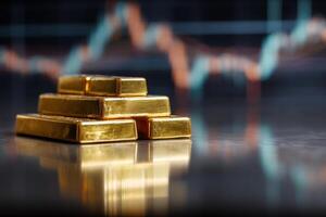 Pyramid of shiny gold bars stacked on reflective surface, with a blurry background showing an out-of-focus graph suggesting economic trends or financial market analysis photo