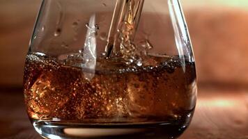 Whiskey is poured into a glass with ice. Filmed on a high-speed camera at 1000 fps. High quality FullHD footage video