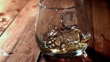 Ice falls into a glass of whiskey. Filmed on a high-speed camera at 1000 fps. High quality FullHD footage video