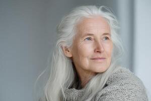 Serene woman with long white hair gazes thoughtfully to the side, wearing a textured gray sweater. Her expression is gentle and peaceful, capturing a moment of calm contemplation photo