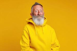 Elderly man with a white beard wearing a bright yellow hoodie and smiling slightly, standing against a yellow background. His hair is neatly styled, giving a lively and cheerful appearance photo