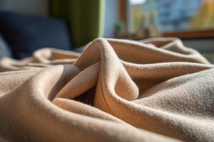 Soft beige fabric with gentle folds, bathed in warm sunlight. The window provides a blurred backdrop. The texture and warmth of the cloth evoke a cozy and inviting atmosphere photo