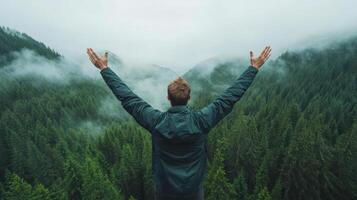 Man with arms raised in the air in front of a forest photo