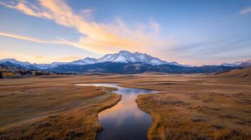 The sun sets over the mountains and a river photo