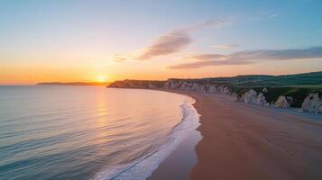 The sun sets over the beach at the edge of the ocean photo