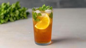 A glass of iced tea with a lemon slice and mint leaves photo