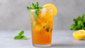 A glass of iced tea with mint leaves and lemon slices photo