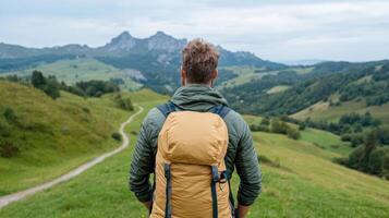 Man with backpack standing on a hill overlooking a valley photo