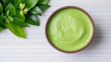 Green smoothie bowl with green smoothie on white wooden table top view photo
