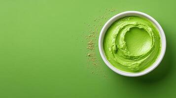 Green smoothie bowl with matcha powder on a green background photo