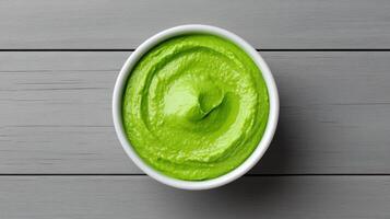 A bowl of green sauce on a wooden table photo
