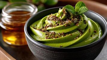 A bowl of green smoothie with a spoon and a jar of honey photo