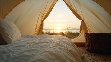 A bed inside a tent with the sun setting behind it photo