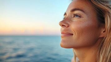 Relaxed woman enjoying sunset by sea, with serene expression and beautiful features photo