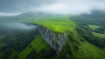 A cliff with green grass and clouds in the sky photo