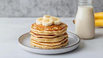 Stack of pancakes with bananas and milk photo