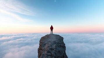 Man standing on top of a cliff looking down at the clouds photo