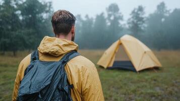 Man in rain jacket standing in front of tent photo