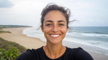 A woman smiling at the camera while standing on a beach photo