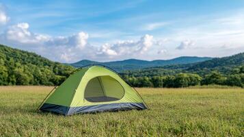 A tent is pitched in a field with mountains in the background photo