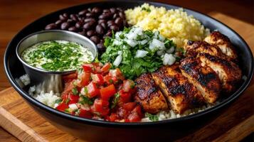 A bowl of rice, beans, chicken, and tomatoes photo