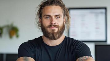 A man with a beard and tattoos sitting at a desk photo