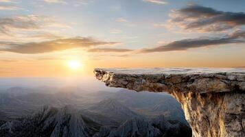 A cliff with a sunset over the mountains photo