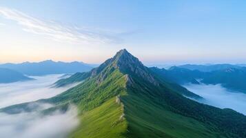 A mountain with a foggy sky and green grass photo