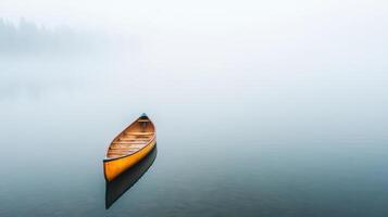 A canoe sits on the water in a foggy lake photo