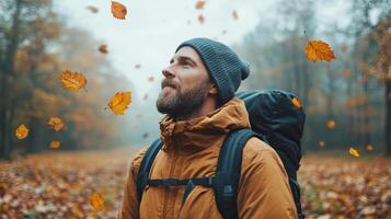 Man with backpack in autumn forest with leaves flying photo