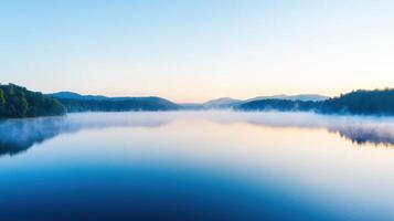 A lake surrounded by trees and fog at sunrise photo