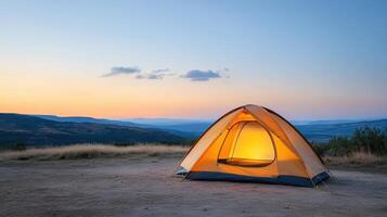 A tent is lit up at sunset in the mountains photo