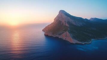 The sun sets over a mountain in the ocean photo