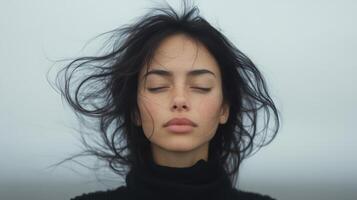 A woman with her eyes closed and hair blowing in the wind photo