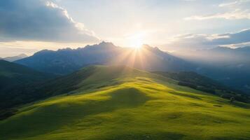 The sun shines over a mountain range with grass and trees photo