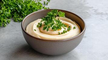 A bowl of creamy dip with parsley on a gray background photo
