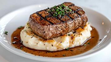 A steak with mashed potatoes on a white plate photo