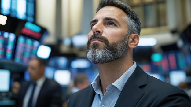 A man with a beard and a suit is looking up at the screen photo