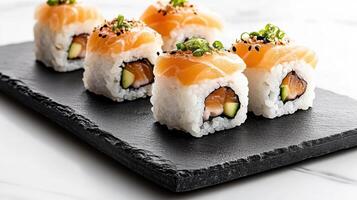 Sushi with salmon and avocado on a black slate plate photo